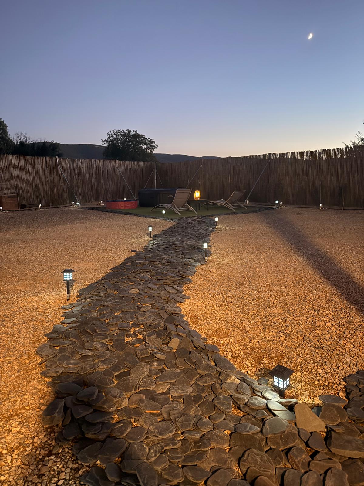 Camino de piedra iluminado en el jardín nocturno de Los Almendros